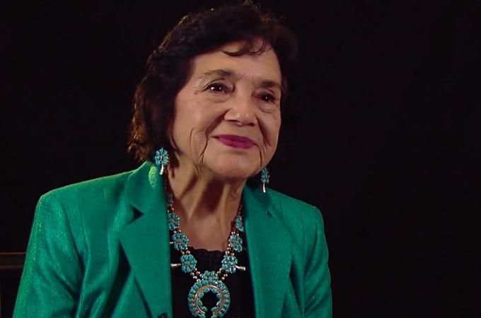 Civil rights activist and labor organizer Dolores Huerta smiles in a green outfit.